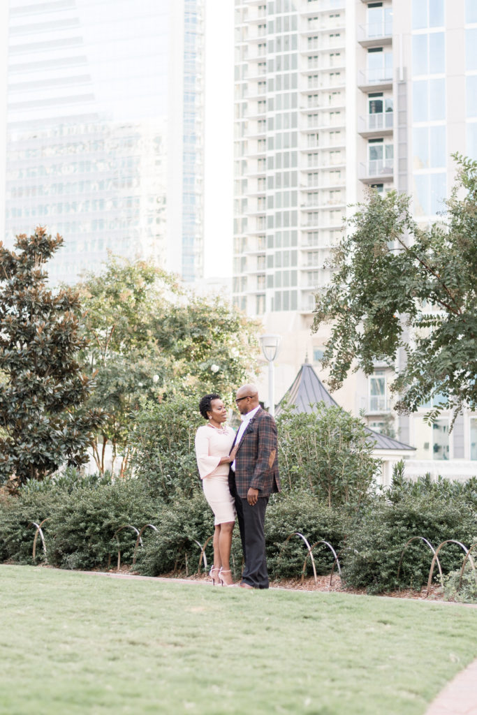 engagement photographer in charlotte capturing couple in romare bearden park in front of uptown skyline