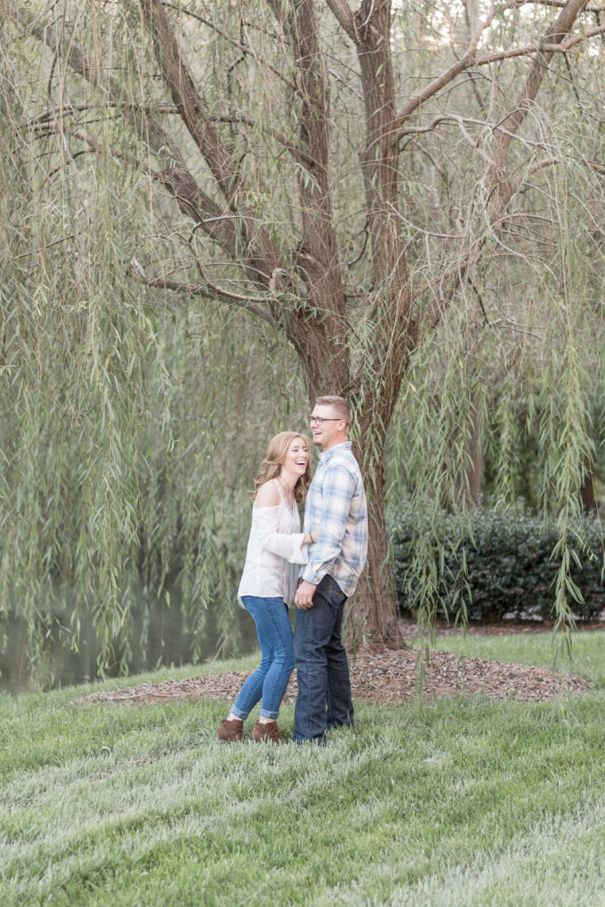 charlotte engagement photography shot of couple under willow tree laughing in charlotte, nc